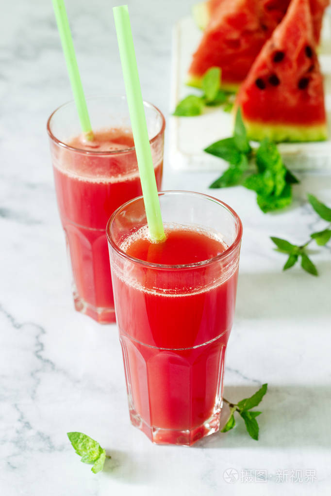 冷西瓜柠檬汁薄荷在玻璃杯和西瓜片在一个光的背景下