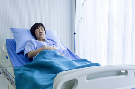 老年妇女患者躺在床上静脉生理盐水。 医疗专业人员与医院病房病人互动。