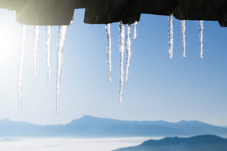 冬季背景与冰柱边界。 晴朗的天气，蓝天和山峰