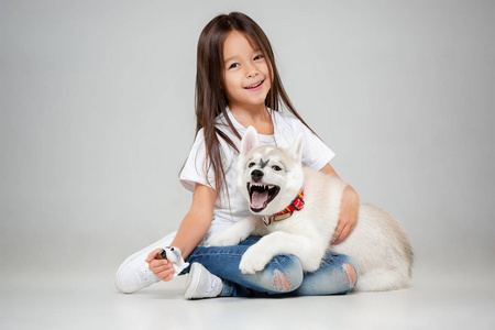 一个快乐的小女孩的肖像与西伯利亚哈士奇小狗在地板上的工作室