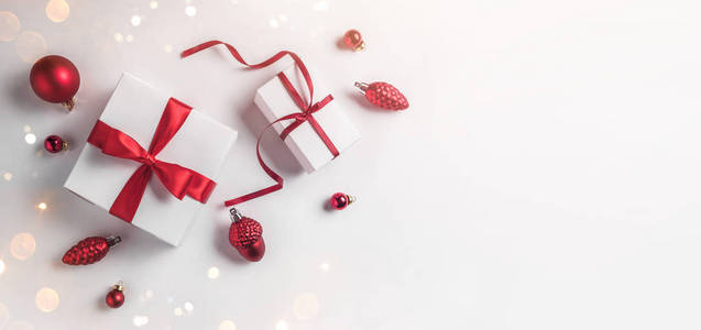 带有红色丝带和白色背景装饰的圣诞礼品盒。 圣诞节和新年快乐主题雪。 平躺式顶部宽幅构图