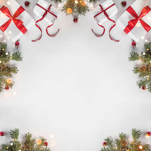 创意框架由圣诞杉枝在白纸背景上与红色装饰松果。 圣诞节和新年主题博克。 平躺式顶部视图