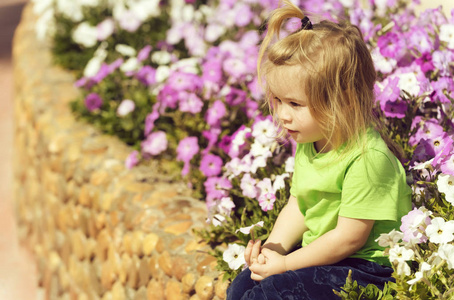 可爱的小宝贝男孩玩在花坛与盛开的花朵