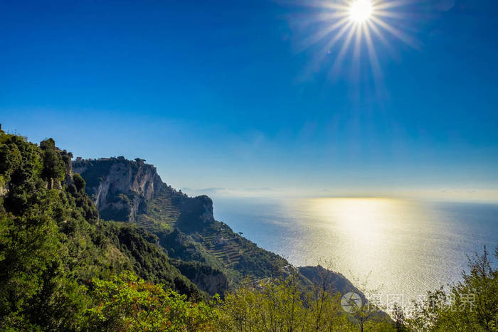 美丽的海景和太阳在蓝天背景上的阿马尔菲海岸