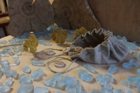 木制手工女巫符文与亚麻袋，蓝色的信纸和黄色的花，以乡村风格