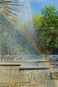 美丽的喷泉与喷气式飞机的节奏，一个游泳池和一个水箱收集水和一个边界在夏季下午的城市背景与彩虹。
