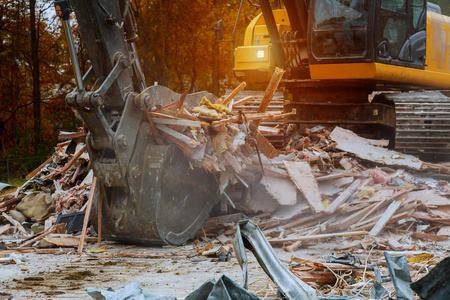 旧房子被一个大反铲木板和瓦砾以及废墟摧毁