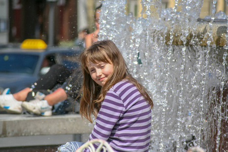 在喷泉附近炎热的夏天里的一个小女孩.照片