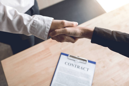 人们握手自信的伙伴关系,人们握手在办公室签订合同.照片