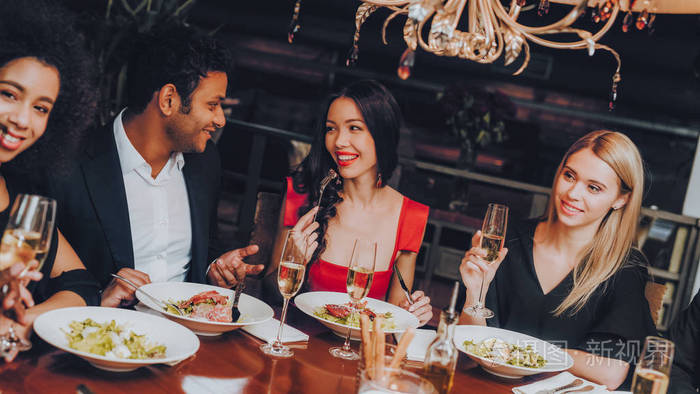 朋友们在餐馆里享受美食. 一群快乐的朋友聚会和吃晚饭.