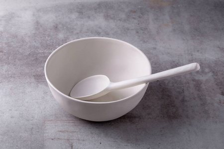 在水泥板上空空白白色陶瓷碗和勺子。
