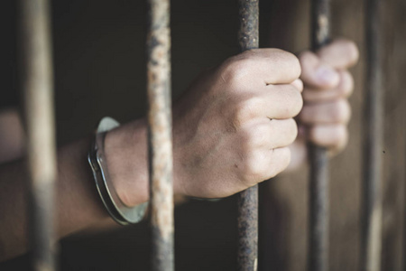 一个囚犯在牢房里抓住一个钢笼，囚犯和警察的概念