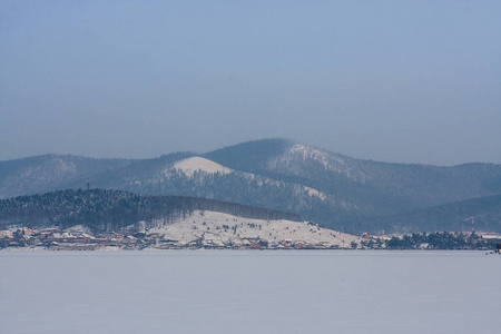 冬季景观。 山湖上霜冻的新鲜空气。 山岸上清澈的雪松和树木。 有自由空间的布局背景