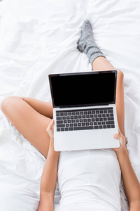 女性使用笔记本电脑的部分视图，在家中的早晨在床上有空白屏幕