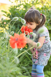 一个三岁的小女孩在花园里闻花的肖像。