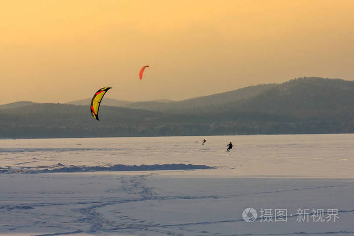 滑雪运动员在设备上控制风筝和极端滑雪板在一个巨大的山湖上。 清新干净的雪和霜冻的景观。 野生自然背景