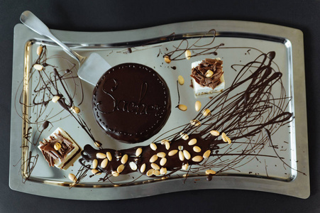 可在银盘上看到带有坚果和糕点的巧克力蛋糕
