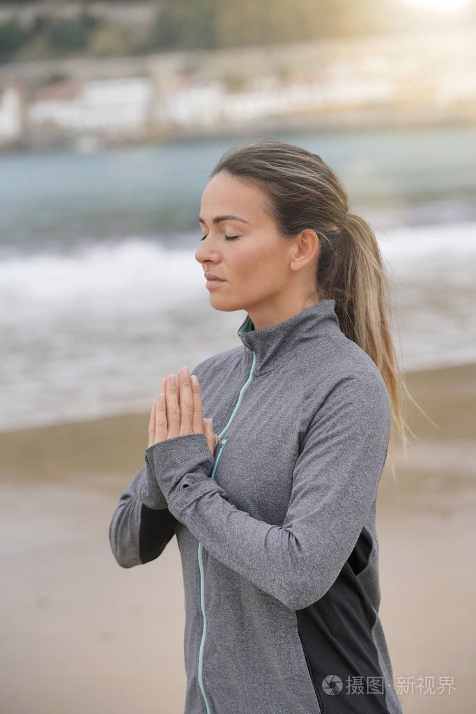 在海滩上打坐运动服的女人