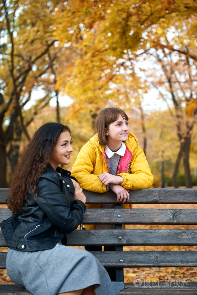 漂亮的女人和十几岁的女孩在秋天公园摆姿势秋天的美丽景色