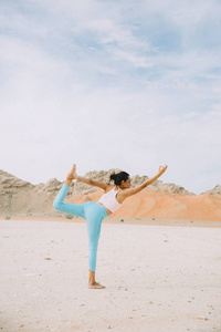 日出时在沙漠和山上做瑜伽的年轻女子