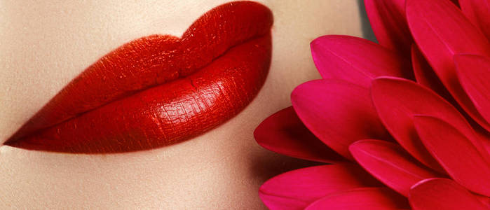 化妆品的化妆和趋势。 嘴唇上有明亮的唇彩和口红。 用红唇妆特写美丽的女性脸。 女性脸上美丽的部分。 红光下完美洁净的肌肤