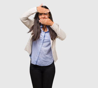 年轻的商业印度女人透过缝隙躲起来眯着眼睛照片