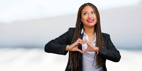 一位年轻的黑人商业女性的肖像，用双手表达爱和友谊的概念，快乐和微笑
