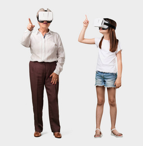 一位老妇人和她的孙女兴奋地玩着虚拟现实眼镜，探索一个试图触摸某物的幻想世界
