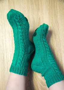 穿着温暖的手工袜子的女人。 针织形成天然羊毛纱。 冬季服装。 在木制的背景上。