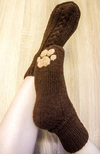 穿着温暖的手工袜子的女人。 针织形成天然羊毛纱。 冬季服装。 在木制的背景上。