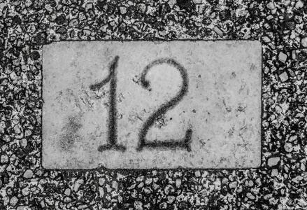 用白色写在黑白方板上的数字。 数字标志固定在房屋外墙上，以指示街道上的地址。 复古设计形象