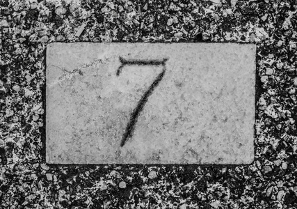 黑色7号，7号隔离在浅灰色或白色墙壁上。 石头的质地。