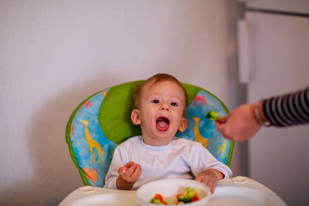 婴儿蔬菜食品。 孩子们吃蔬菜。 微笑的小男孩吃健康的蔬菜