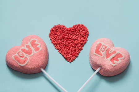 情侣情人节棒棒糖粉红色糖果棒与爱的文字在蓝色背景。 有趣的概念。 快关门。