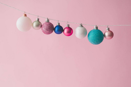 彩色粉彩圣诞装饰球在粉红色背景。 最小新年概念