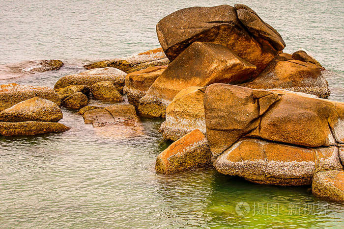 一堆大石头黑褐色的天气把海藻和贝壳打在开阔的海面上