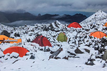 雪地里五颜六色的帐篷。 登山者在帐篷里等坏天气。 埃尔布鲁北部斜坡的大本营