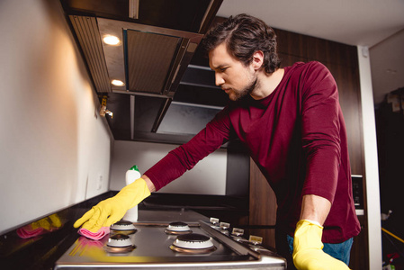 严肃的男人，橡胶手套清洁厨房