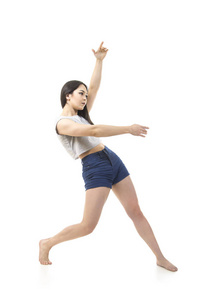 一个穿短裤和t恤跳舞的年轻女孩跳现代芭蕾。拍摄于白色背景。孤立的图像。