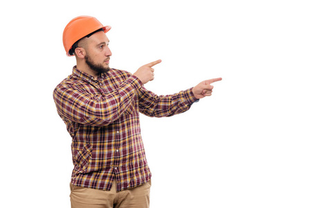 建筑工人在防护建筑橙色头盔手指向右边隔离在白色背景。 复制文本空间。 该工作了。