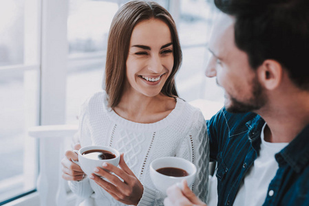 幸福的夫妇在咖啡馆里休息。 夫妻是美丽的年轻男女。 人们坐在桌子旁。 人们互相微笑。 人们从杯子里喝茶。 阳光明媚的白天。