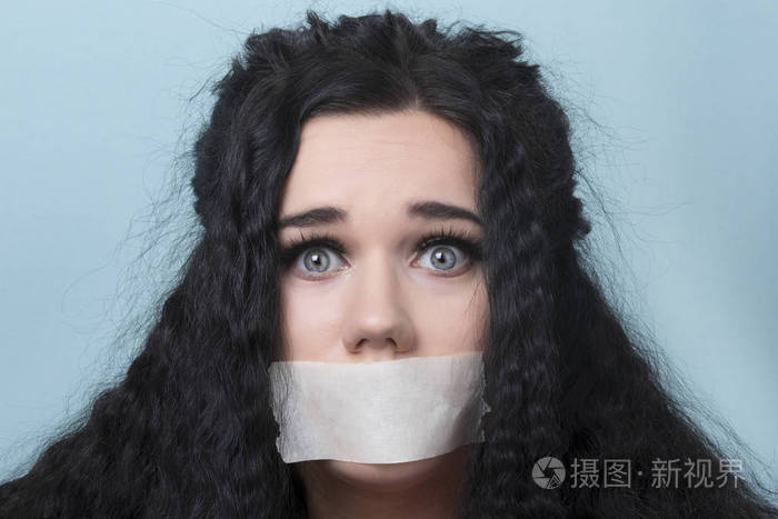 年轻女子的肖像,嘴和嘴唇密封在胶带上,受到限制和虐