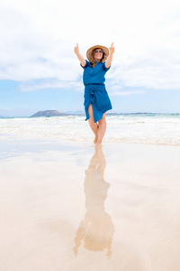 一位穿着蓝色裙子的快乐旅行者女士享受她的热带海滩度假