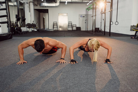 体育运动员和女运动员一起在健身房做俯卧撑。