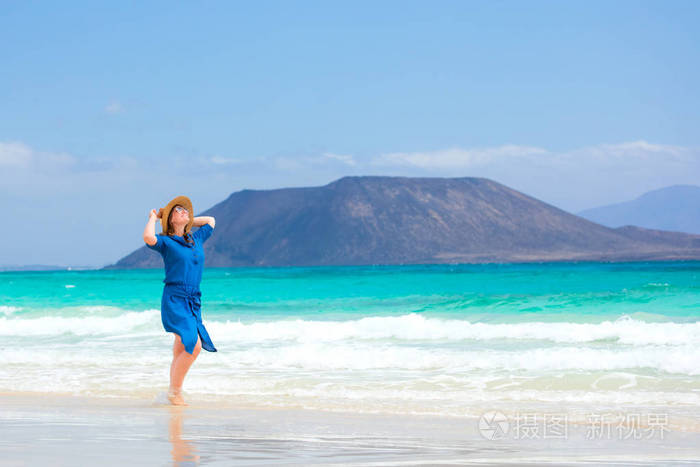 一位穿着蓝色裙子的快乐旅行者女士享受她的热带海滩度假