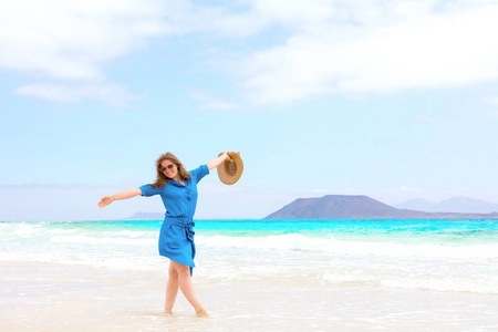 一位穿着蓝色裙子的快乐旅行者女士享受她的热带海滩度假