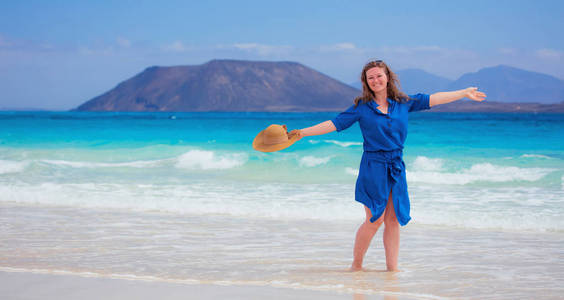 穿着蓝色衣服的快乐旅行者女人享受她的热带海滩度假