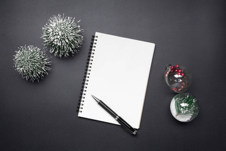 打开空白笔记本笔圣诞球和迷你圣诞树黑色色调。 节日圣诞节和新年概念。