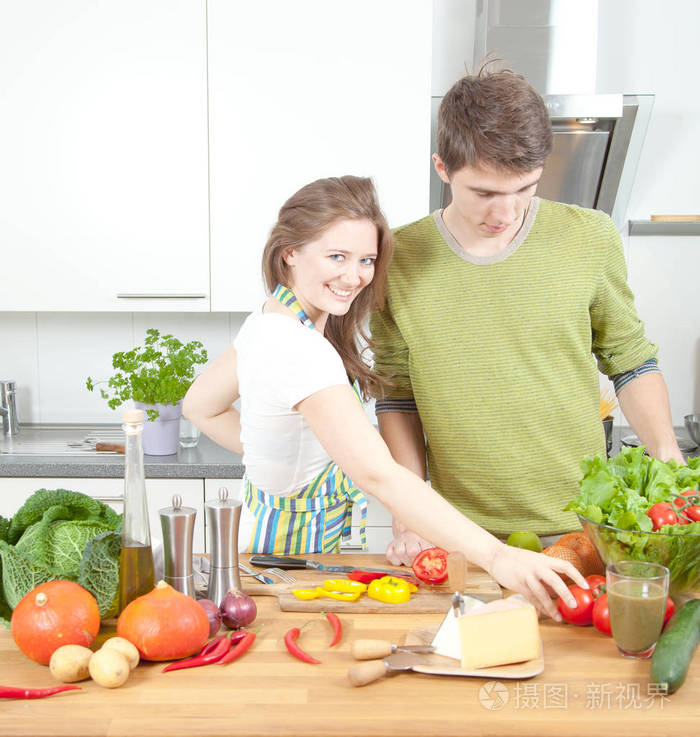 快乐运动的夫妇正在轻厨房准备健康的食物。健康食品概念