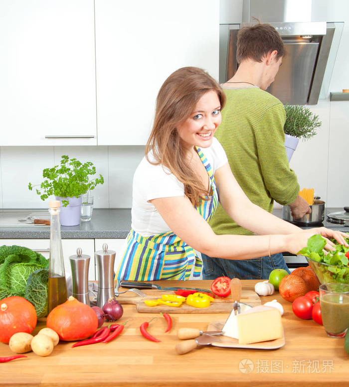 快乐的运动夫妇正在轻厨房准备健康的食物。 健康食品概念